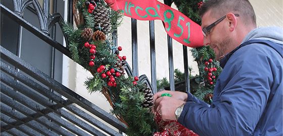 Man hanging up wreath on a balcony railing